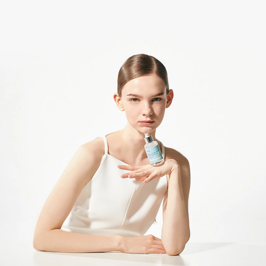 Woman holding a bottle of skincare product against a white background
